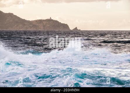 Mer Méditerranée orageux à Punta Caldanu près de Lumio dans le Balagne région Corse avec le phare de Revellata in la distance Banque D'Images