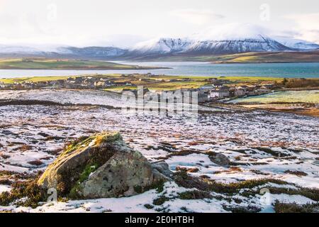 Vue d'hiver sur les îles écossaises sur Orkney avec la ville de Stromness au-dessous de la colline et grande pierre en premier plan Banque D'Images