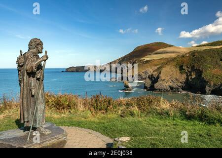 La statue de Saint Carannog garde la vue sur la baie de Llangrannog, avec la dent de Bica et la pointe de Ynys Lochtyn en arrière-plan. Banque D'Images