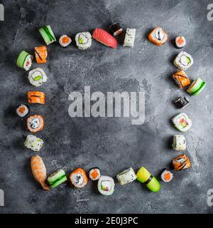 Cadre sushi sur fond sombre. Petits pains à sushis, nigiri, steak de saumon cru, riz et avocat. Pose à plat. Vue de dessus Banque D'Images