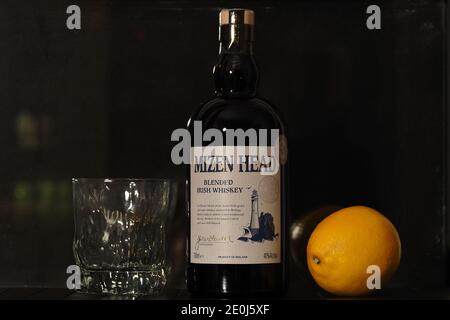 Une bouteille de whisky irlandais et de citron sur fond noir. Banque D'Images