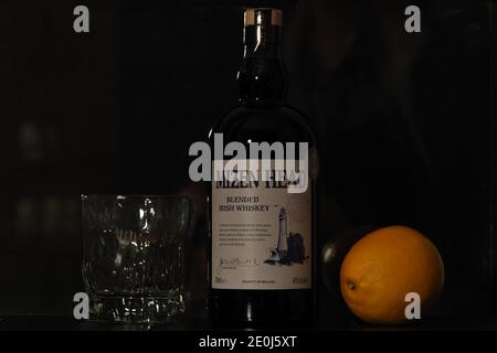 Une bouteille de whisky irlandais et de citron sur fond noir. Banque D'Images