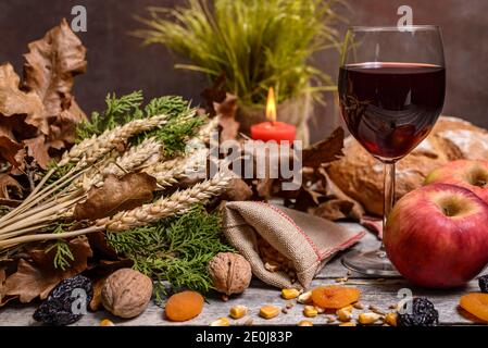 Cuisine traditionnelle pour la veille de Noël orthodoxe. Yule log ou badnjak, vin, pain, pommes, céréales, fruits secs et bougie sur table rustique. Conce Banque D'Images