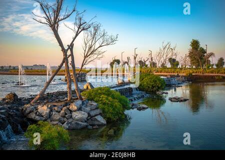 Un lac artificiel au milieu du désert aux Émirats arabes Unis. Belle vue sur le lac artificiel et le ciel bleu avec une nature verte et des fontaines d'eau. Expo 2020 Banque D'Images