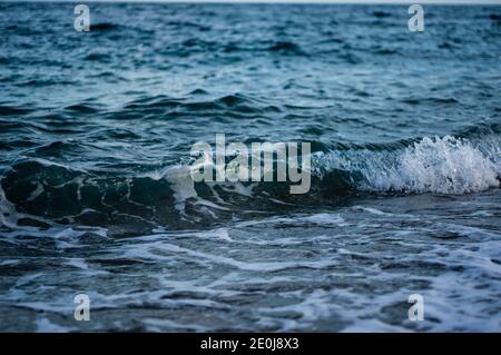 De petites vagues dans la mer freinant à la plage. Turquise, eau claire dans une mer de tempête avec spray. Banque D'Images