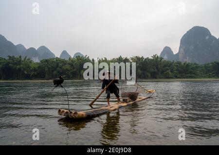 Pêche au cormoran sur la rivière Li avec des sommets karstiques lointains, Guilin, Chine Banque D'Images
