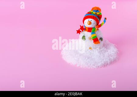 Bonhomme de neige et paysage de neige minimal en hiver sur fond rose clair. Concept de vacances d'hiver. Banque D'Images