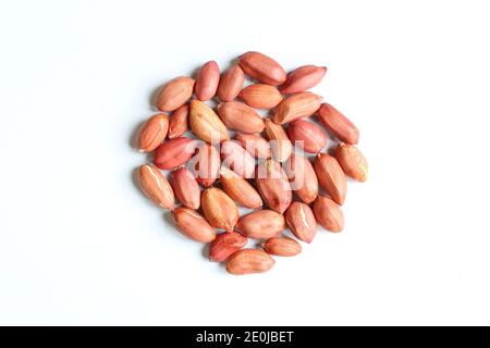 Arachides rouges en husk. Pile de noix non pelées isolée sur fond blanc Banque D'Images