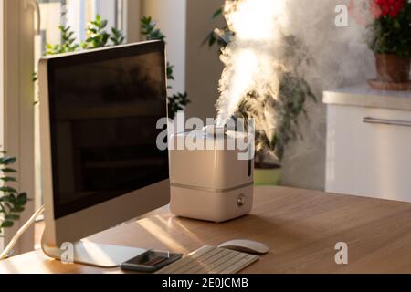 Gros plan du diffuseur d'huile aromatique sur la table à la maison, vapeur de l'humidificateur d'air. Technologie ultrasonique, augmentation de l'humidité de l'air à l'intérieur, édredon Banque D'Images