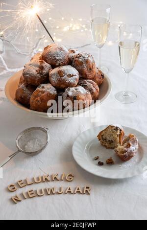 Gelukkig Nieuwjaar (traduction : bonne année) écrit avec de petites lettres et un bol d'oliebollen traditionnel (Beignets de pâte hollandais) avec des séparateurs Banque D'Images