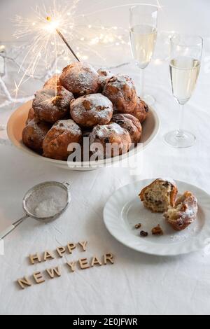 Bonne année écrite avec de petites lettres et un bol D'oliebollen traditionnel (beignets de pâte hollandais) avec des sparkers et deux verres de champage Banque D'Images