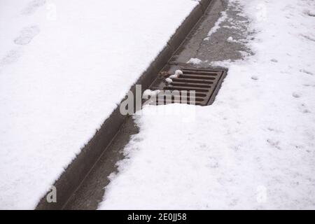 2 - route couverte de neige épaisse avec seulement le drain du trottoir. À mesure que la neige fond, la région risque d'être inondées de toute l'eau. Banque D'Images