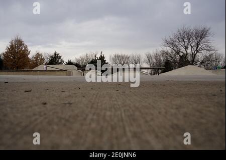 Une grande photo au niveau du sol d'un rail dans un parc de skate par une journée nuageux. Le béton s'inclinera en arrière-plan. Banque D'Images