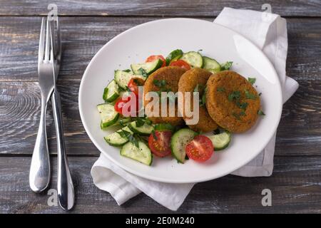 Côtelettes de carottes à l'amarante, salade de concombres frais et tomates sur une table en bois. Délicieux plats maison sains Banque D'Images