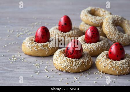 Biscuits traditionnels grecs de Pâques avec graines de sésame et œufs de couleur sur la table en bois, foyer sélectif, espace libre Banque D'Images