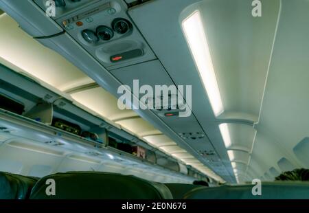 Accent sélectif sur la lampe de lecture au pavillon dans un avion commercial sur un casier de rangement au pavillon flou avec porte ouverte. Avion Banque D'Images