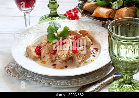 Poulet satsivi sur fond de bois blanc avec des graines de grenade Banque D'Images