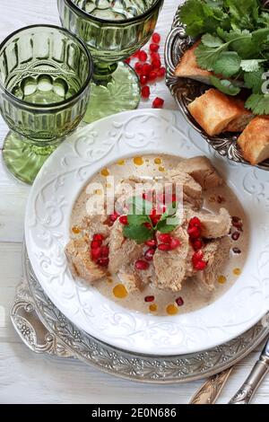 Poulet satsivi sur fond de bois blanc avec des graines de grenade Banque D'Images