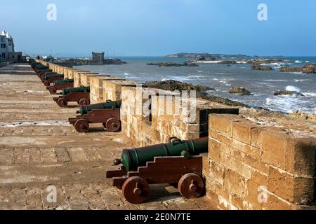 Le soleil s'élève sur une rangée de canons à l'ancienne forteresse d'Essaouira au Maroc. Les canons sont orientés vers l'océan Atlantique. Banque D'Images