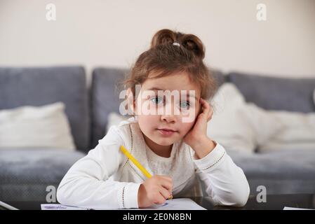 Une petite fille regarde l'appareil photo qui repose la tête sur sa paume Banque D'Images