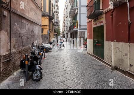 Une ruelle étroite dans les ruelles de Naples, avec des cyclomoteurs garés, en Italie Banque D'Images