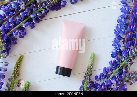 Bouteille de maquette pour marquage et étiquette. Lupin fleurs et mockup / modèle 3d de bouteille rose Squeeze tube plastique avec capuchon noir. Vue de dessus. Orga naturel Banque D'Images