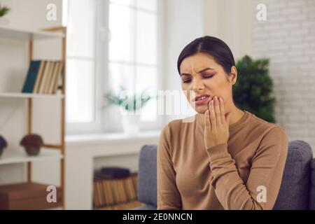 Femme souffrant de mal de dents ou de sensibilité des dents et touchant la joue avec la grimace de la douleur Banque D'Images