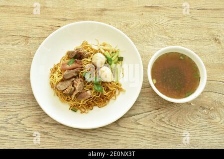 Nouilles aux œufs jaunes chinoises avec garniture de porc braisé et boule assiette avec os dans une tasse à soupe d'herbes brunes Banque D'Images