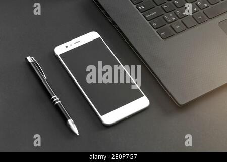 Stylet, téléphone portable et clavier d'ordinateur portable sur un bureau gris/noir - vue du dessus Banque D'Images