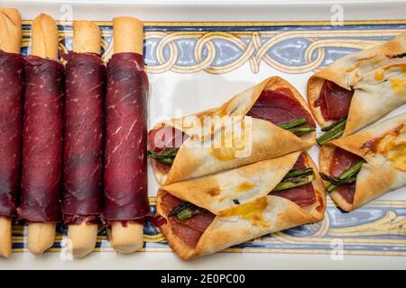 Vue imprenable sur les canapés au jambon salé avec asperges sauvages enveloppées d'un gâteau au maïs cuit et de petits pains cecina. Cuisine méditerranéenne Banque D'Images