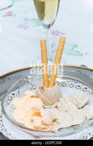 Vue fermée à 45 degrés de vanille et de mandarine naturelle crème glacée avec un verre de champagne et nappe blanche en arrière-plan Banque D'Images