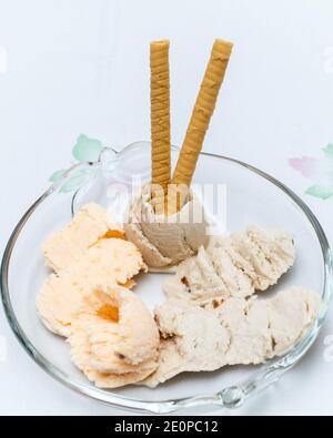 Vue verticale sur la glace mandarin. Crème glacée à la banane et au rhum avec des sultanines et deux gaufrettes servies sur une assiette en verre. Concept de fond frais, été 2 Banque D'Images