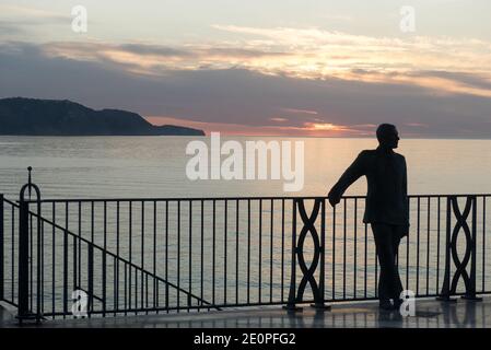 Nerja en Espagne : statue de bronze du roi Alfonso XII sur le balcon de Europa, silhouetée par le soleil levant. Banque D'Images