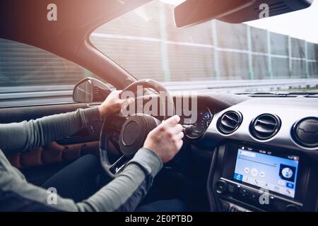 Les mains de l'homme sur le volant d'une voiture en mouvement. Banque D'Images