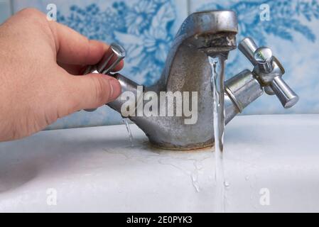 L'eau fuit d'un vieux robinet rouillé dans la salle de bains, la plomberie de la maison. Banque D'Images