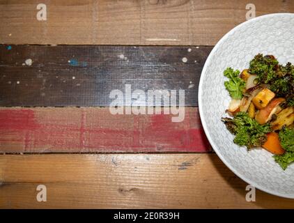 Une délicieuse assiette de rôtis racines avec Apple Kale et Chips Seeds sur un plan de travail en bois de cuisine Banque D'Images