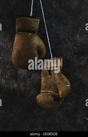 Vieux gants de boxe bruns suspendus au mur Banque D'Images