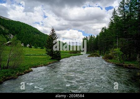 Vue sur la rivière Claree dans les Hautes-Alpes France.les rives sont couvertes d'herbe, en arrière-plan, certaines montagnes sont encore recouvertes de neige. Banque D'Images