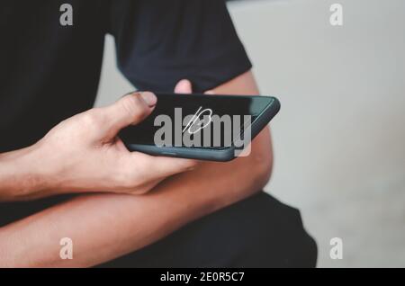 Homme tenant l'icône du nuage de téléphone mobile.Téléchargement de l'application de réseau social en ligne. Banque D'Images