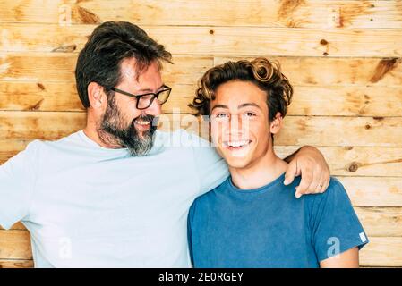 Portrait de père et de fils - générations d'adultes et de jeunes adolescents souriez et câlin avec un fond en bois - jeune et concept âge mûr Banque D'Images