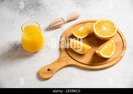 Tranches d'oranges fraîches avec alésoir en bois sur fond de marbre Banque D'Images