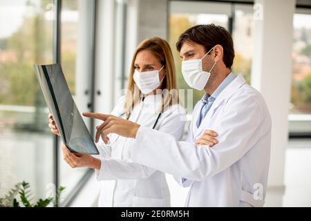 Équipe de médecins avec masques protecteurs pour le visage examinant la radiographie dans le bureau Banque D'Images