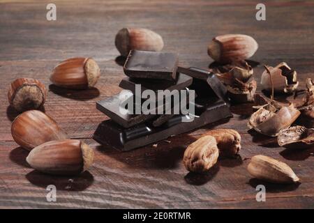 Chocolat noir et noisettes. Barre de chocolat cassée sur la table de cuisine noire Banque D'Images