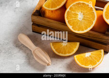 Tranches d'oranges fraîches avec alésoir en bois sur fond de marbre Banque D'Images