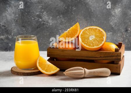 Tranches d'oranges fraîches avec alésoir en bois sur fond de marbre Banque D'Images