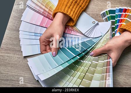 Roue de couleur pour choisir le ton de la peinture. Les mains d'une décoratrice d'intérieur féminine travaillant avec la palette pour choisir les couleurs. Concept de processus créatif. Comparaison Banque D'Images