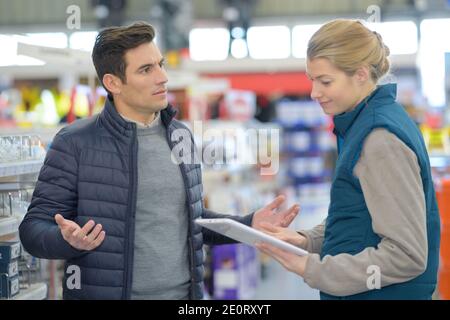 le client et le vendeur choisissent un marteau dans un magasin domestique Banque D'Images