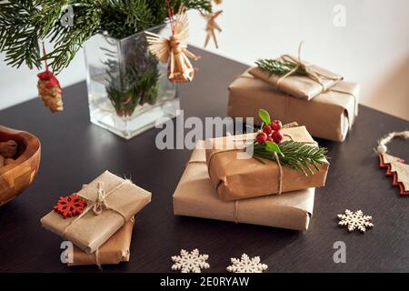 Cadeaux de Noël enveloppés de papier recyclé écologique avec décoration en bois sous les branches de sapin avec ornements en paille Banque D'Images