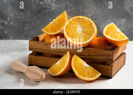 Tranches d'oranges fraîches avec alésoir en bois sur fond de marbre Banque D'Images