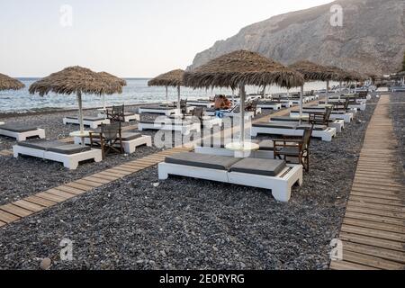 Santorini, Grèce - 18 septembre 2020 : chaises longues sur la plage de sable volcanique noir de Kamari à Santorin. Cyclades, Grèce Banque D'Images